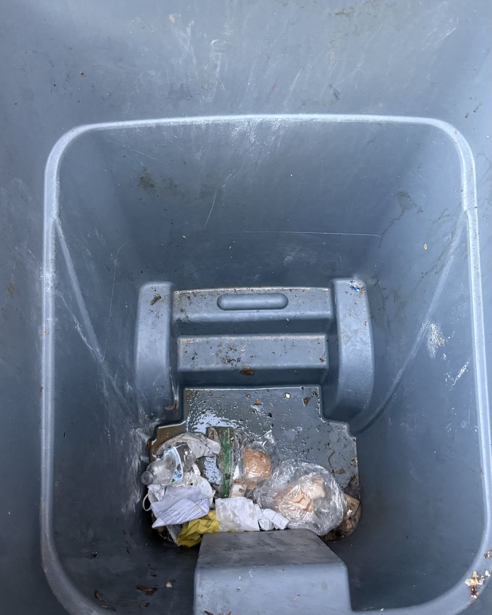 Inside of a bin before cleaning, with leftover trash and grime at the bottom.